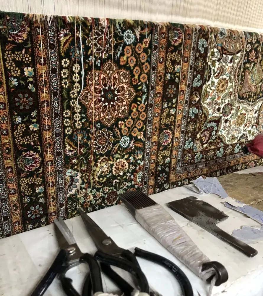 Hand-finishing tools beside a detailed handmade silk rug