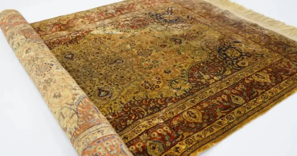 Hand-knotted silk rug rolled back to show its fine pattern and silk surface