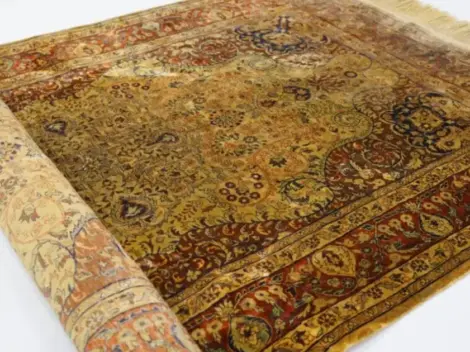 Hand-knotted silk rug rolled back to show its fine pattern and silk surface
