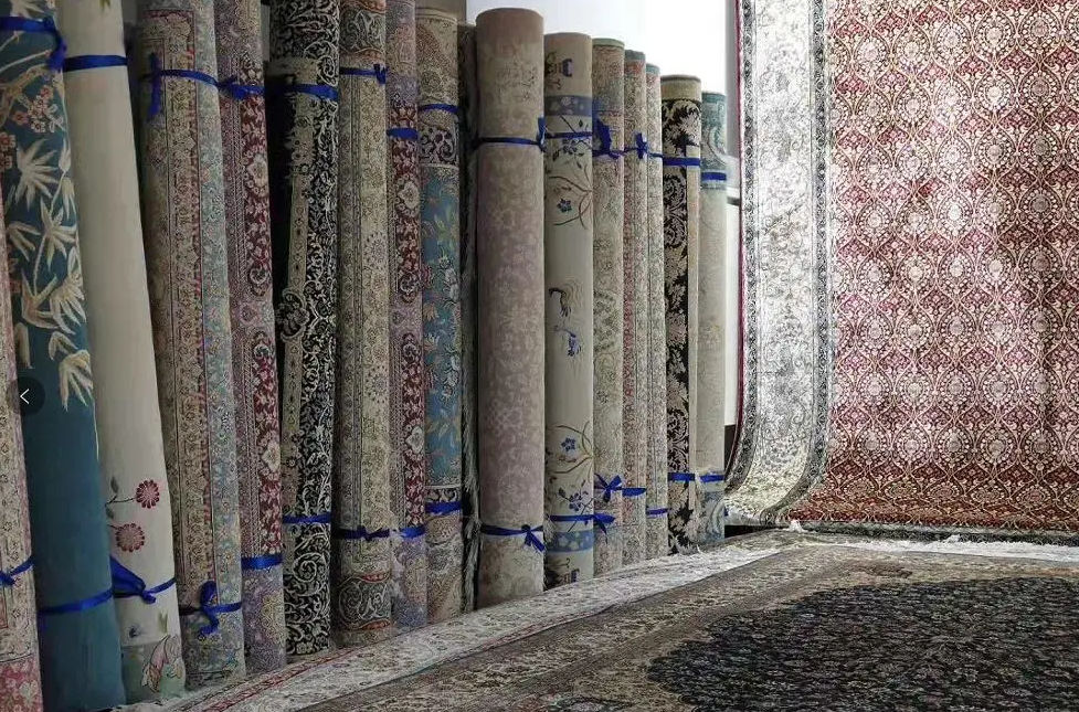 Finished handmade silk rugs rolled and displayed in stock