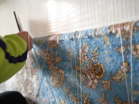 Artisan weaving a handmade silk rug on a vertical loom