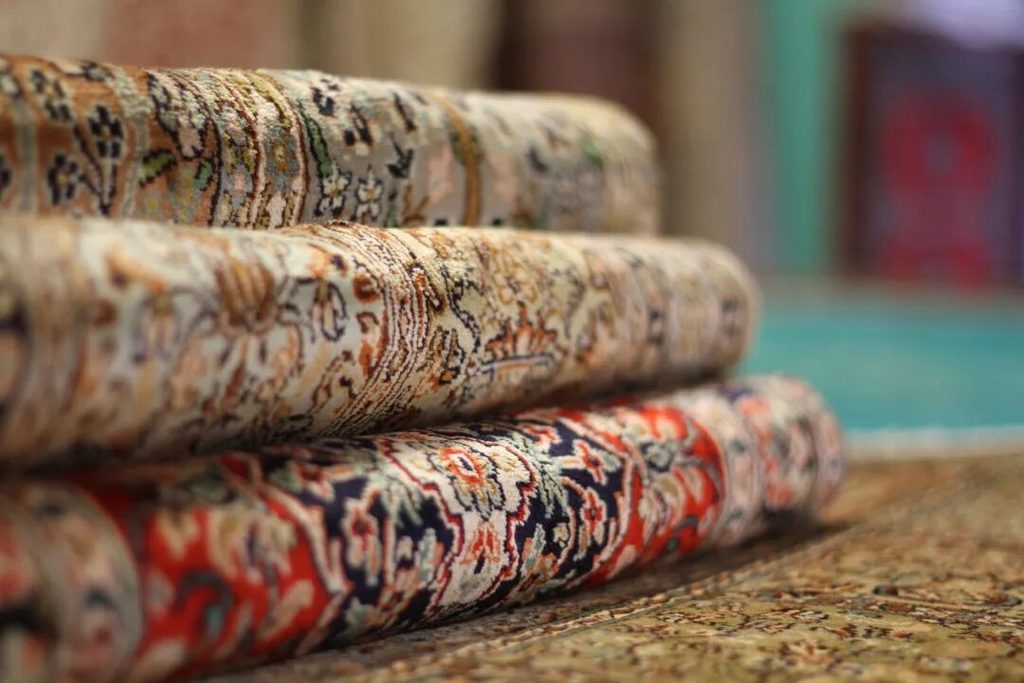 Close-up of several rolled patterned rugs