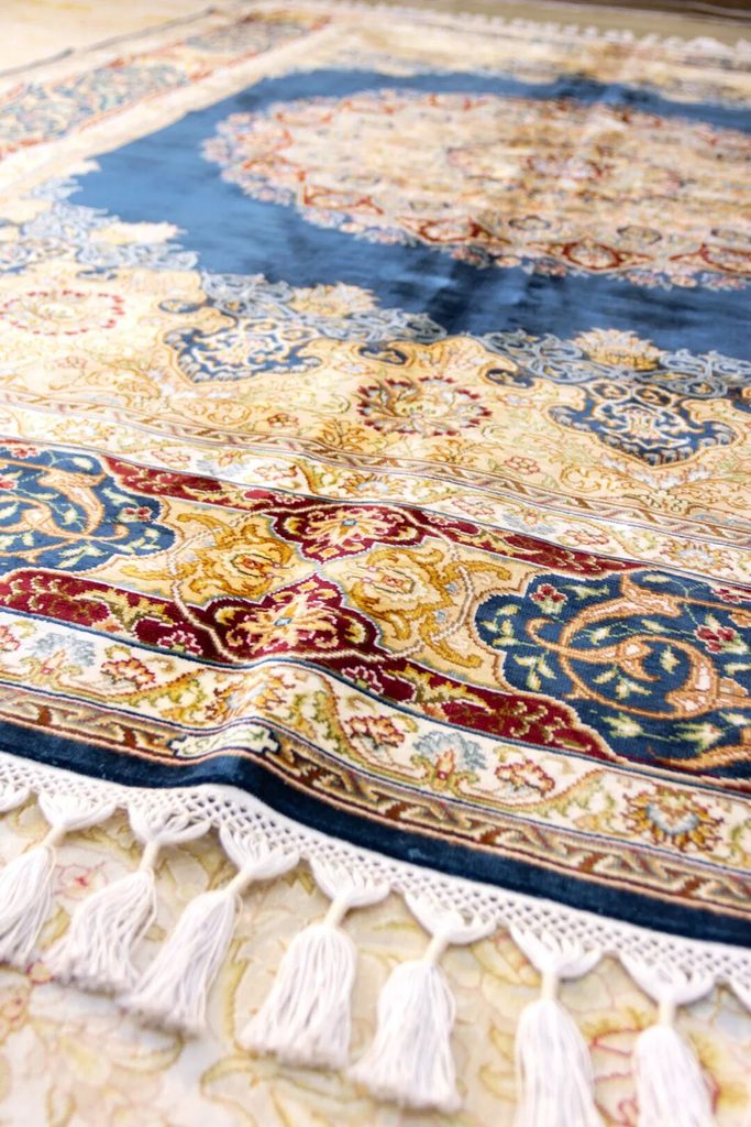 Close-up view across patterned rug surfaces and fringed edges