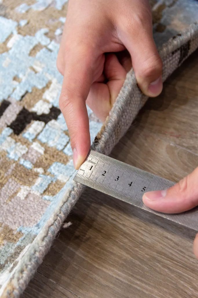 A ruler measuring the edge thickness of a patterned rug