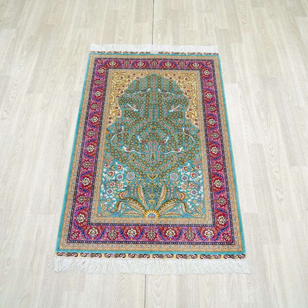 A complete hand-knotted silk rug laid flat on a light floor