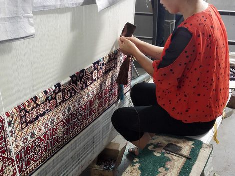 A complete hand-knotted silk rug laid flat on a light floor