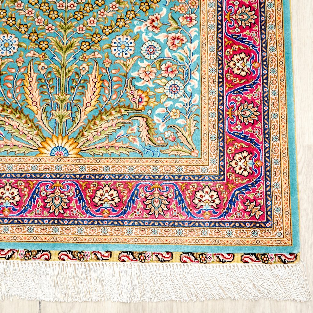 Detailed floral border and fringe on a hand-knotted silk rug